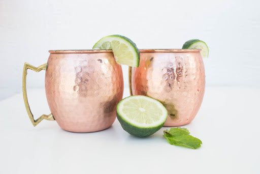 two Moscow Muled copper mugs condensation on the outside with sliced lime wedged on its rim