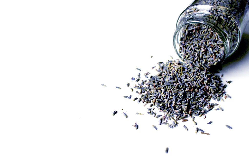 A jar of lavendar being poured out on a white table. 