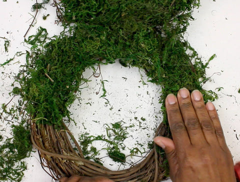 press moss onto hot glue for DIY moss bunny wreath