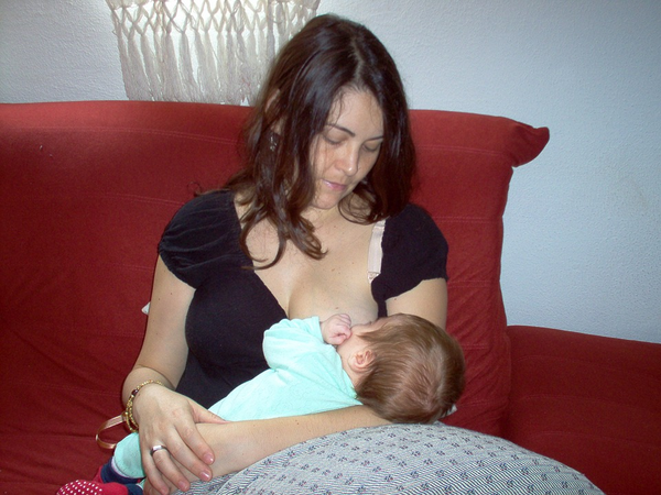 Mom breastfeeding child on a big red couch