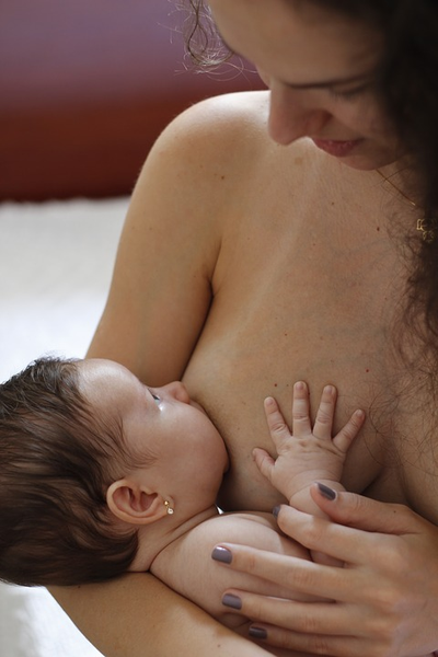 Topless mother breastfeeding baby with pierced ears