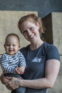 Mutter trägt Baby beim Sport auf dem Arm