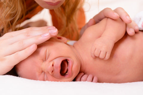 Mutter streichelt schreiendes Baby am Kopf