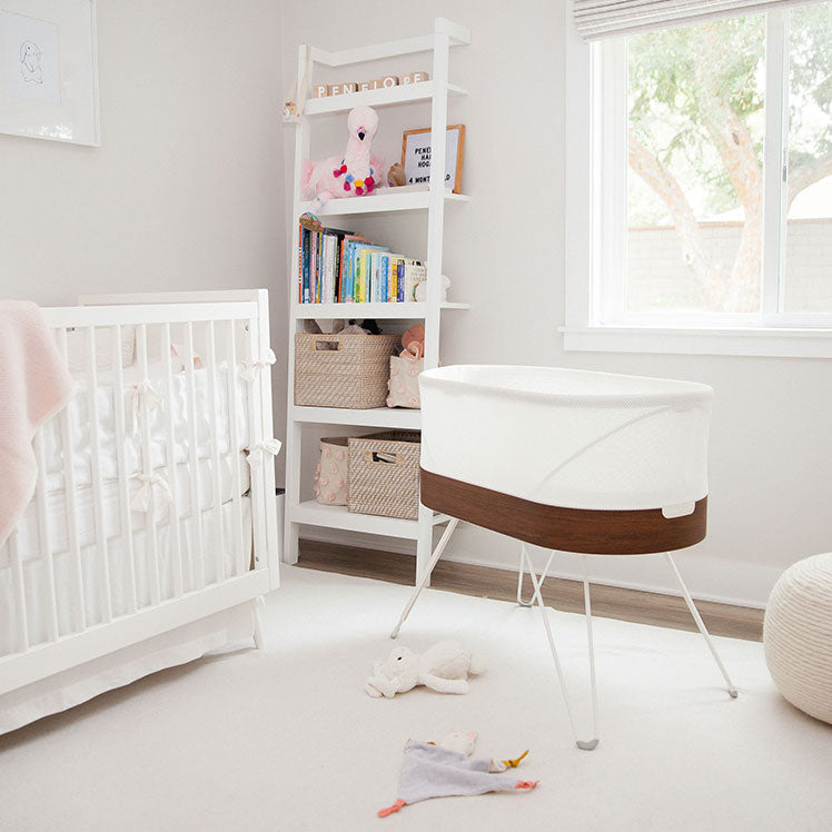 baby nursery with SNOO bassinet, white crib and white bookshelf