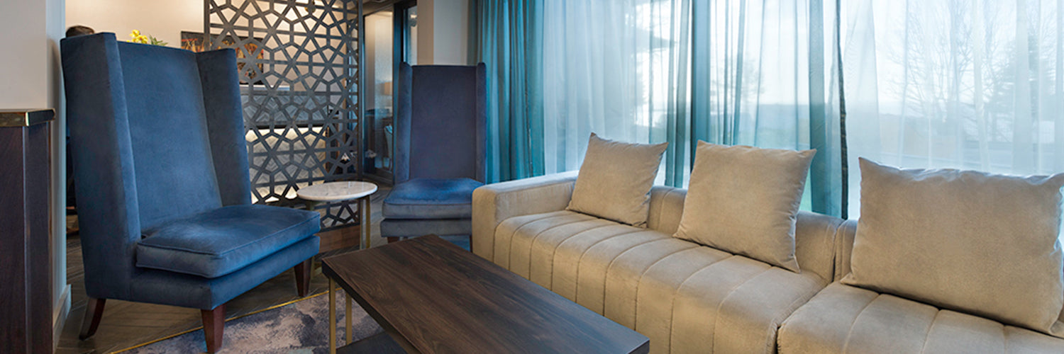Teal high back lounge chair and beige sofa in bar area