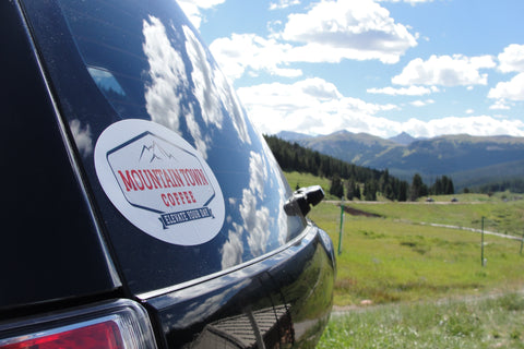 Rear window of car with Mountain Town Coffee bumper sticker in lower left corner