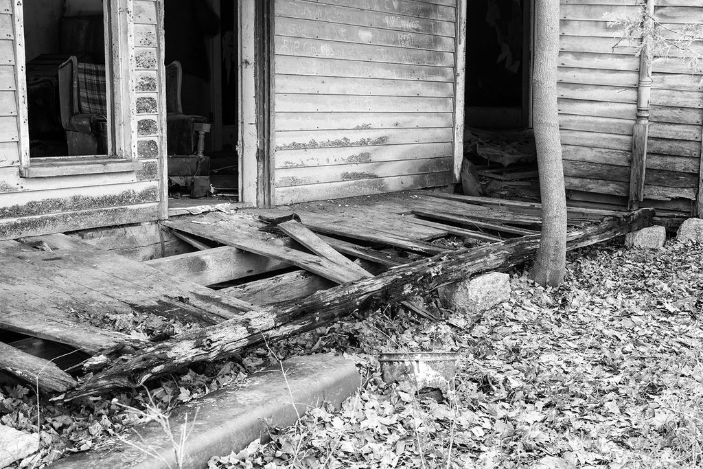 Broken porch of abandoned farmhouse. Black and white photograph by Keith Dotson.