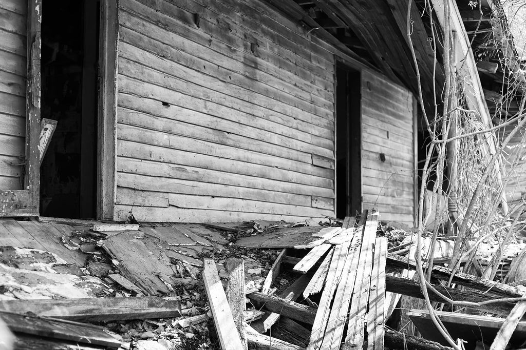 Collapsing back porch of an abandoned farmhouse. Black and white photograph by Keith Dotson.