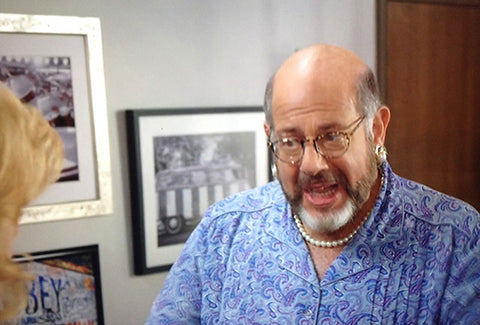 In this scene, the photo is seen over the shoulder of Maria’s agent, Bruce, played by Fred Melamed.
