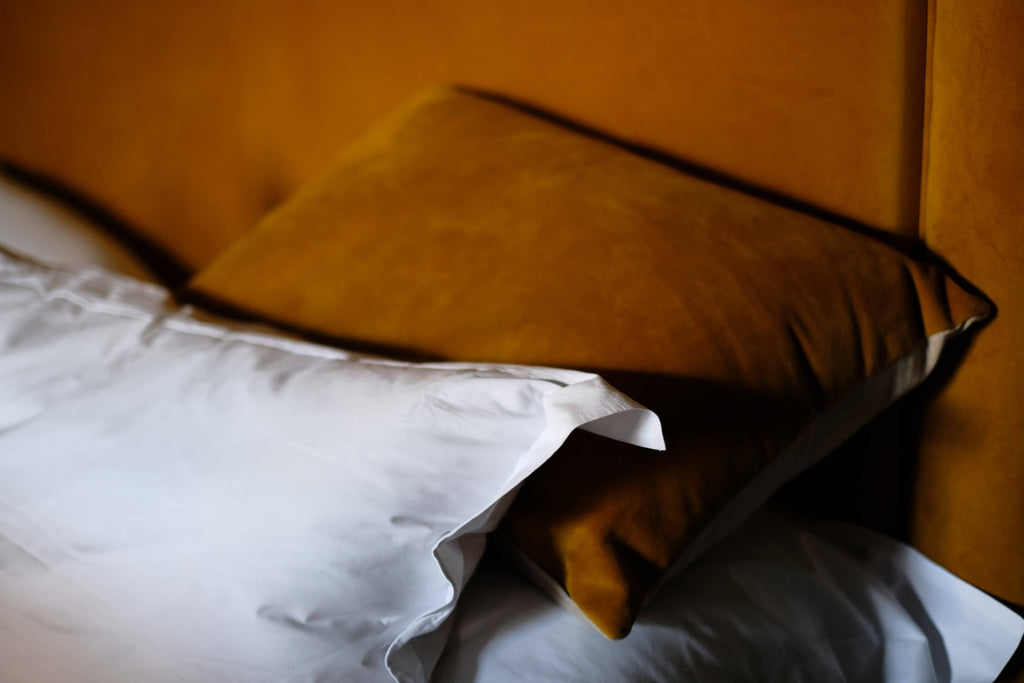 leather brown pillow leaning on a brown headboard white duvet