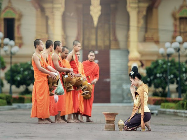 charity- woman bows down to the buddhist monks