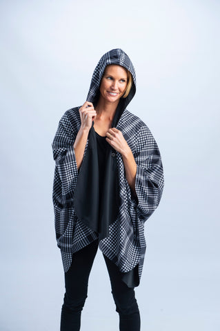 Woman wearing a black & white houndstooth print RainCaper with the hood up