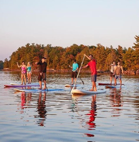 A large group of stand up paddle boarders on a lake