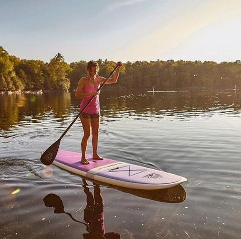 a female stand up paddle boarder on a hard board in a lake