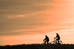 2 people getting exercise by bicycles at sunset