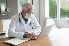 Dr. wearing mask at his desk.