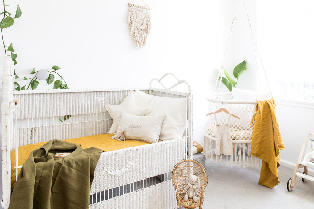 gender neutral nursery featuring mustard and olive shades, macrame hanging bassinet and vintage rattan cot. Baby bedding by little willow vintage