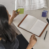top view of a woman taking notes in The MERCER™ Refillable Journal - Small - Blue