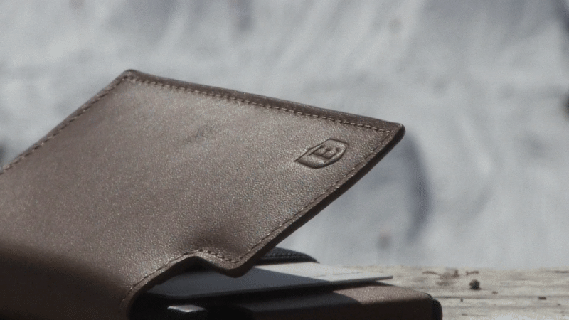 Animated gif of a skier doing a slope in the background, with a smart travel wallet in focus.