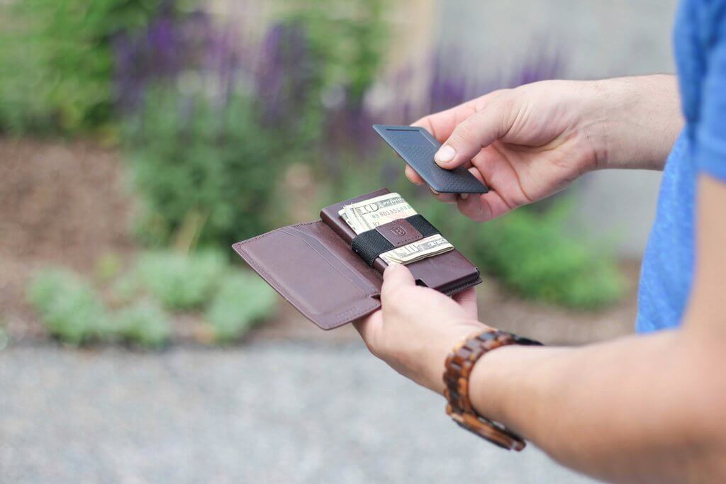 image of a man holding a handmade men's leather wallet and a wallet tracker.