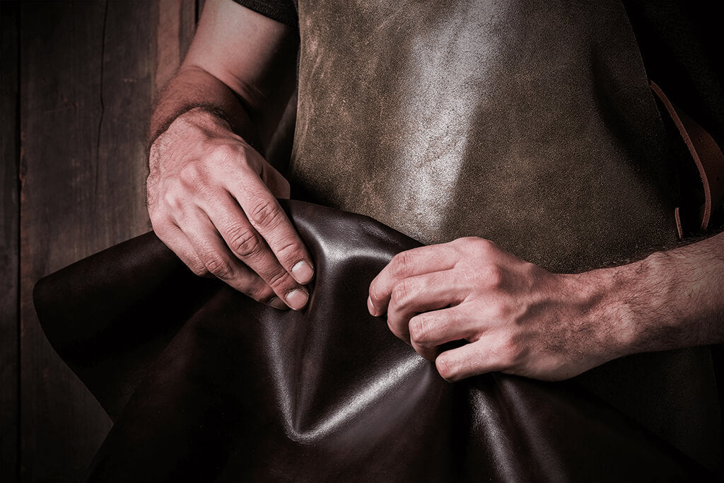 Image of a man holding a leather hide, soon to be made into a handcrafted wallet.