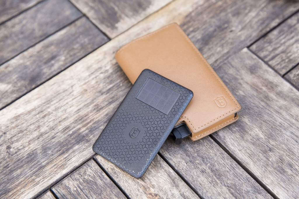 Image of a safe wallet and a GPS crowd tracker, placed on a wooden table background.