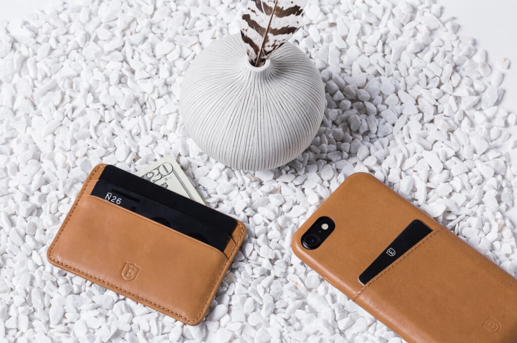 Image of an innovative wallet and cardholder with a dollar note tucked behind it, on a white background.
