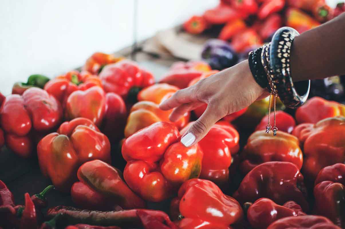woman's hand reaching out for red bell peppers