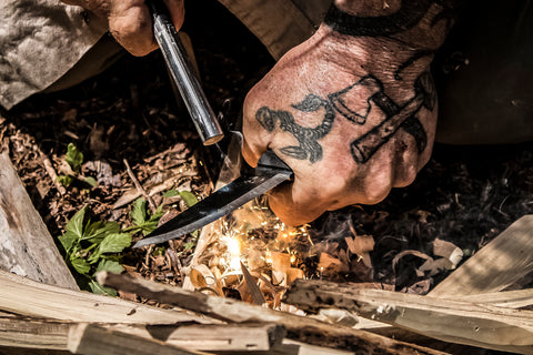 A survival knife being used to scrap a ferro rod