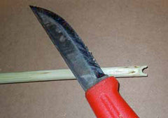 A survival knife cutting out an arrow nock