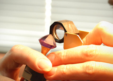 Photo of a gem cutter inspecting the gems before sending it to the polish