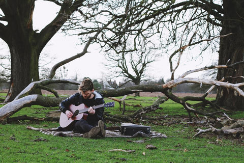 A man playing a guitar in forest