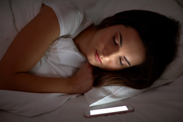 Woman asleep with smartphone turned on and shining light on her face