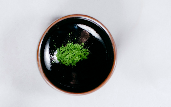 vibrant green matcha powder in a bowl chawan matcha bowl, on a white countertop surface