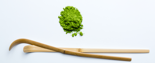 round pile of premium quality matcha with two hand-carved bamboo Japanese tea scoops