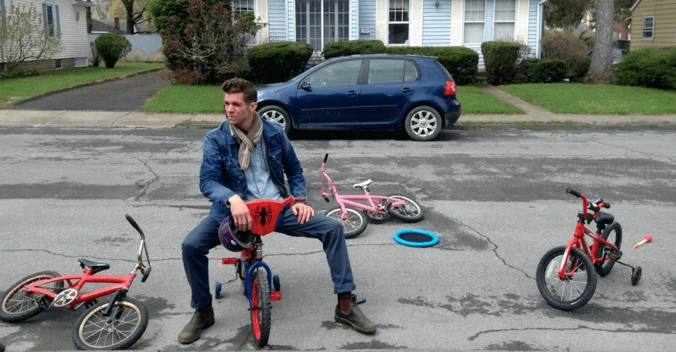 artist joseph ferm on kids bicycle in street