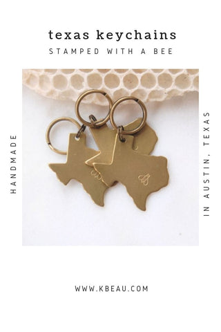 Three Texas shaped keychains with honeybee stamped on them lying on white background with honeycomb kbeau jewelry