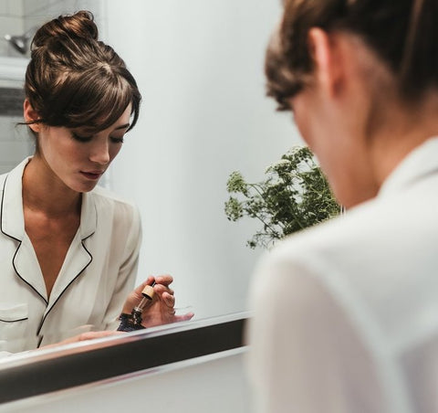 woman applying Midnight Shift Facial Oil in mirror