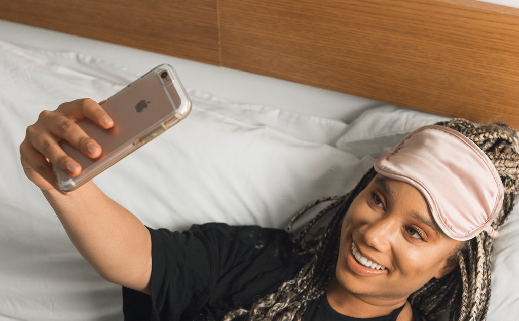 girl wearing a sleep mask on forehead taking selfie with iphone