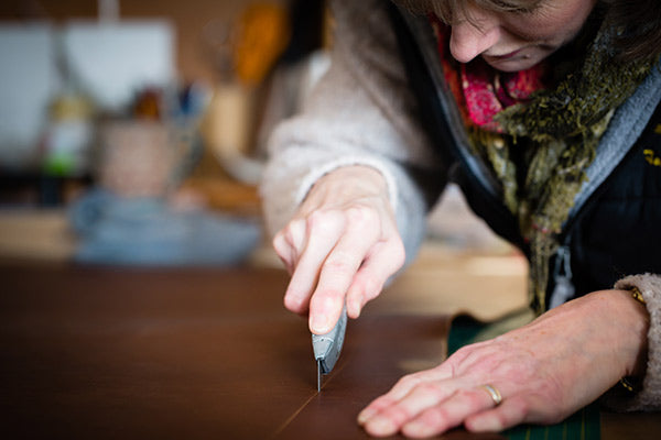 Jackie cutting out leather for a portfolio