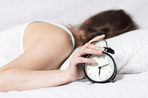 photo of a woman turning off her alarm clock because she is trying to sleep.