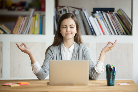 image of a women meditating at laptop with serene look.