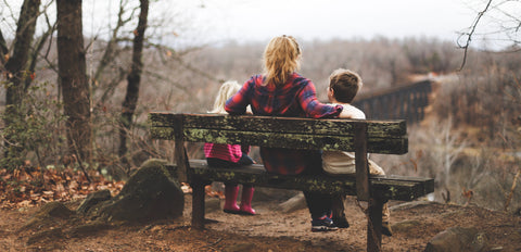 a mom and her children sitting on the bench.