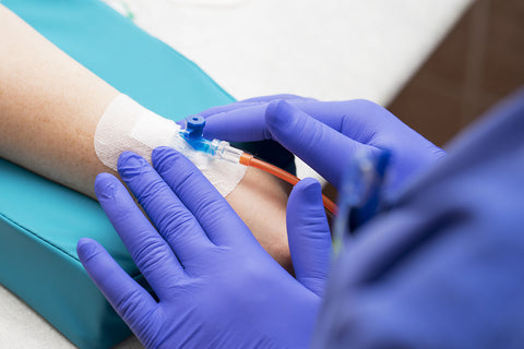 photo of gloved hands placing a catheter in an arm.