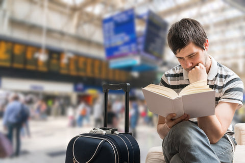 photo of a man reading a book at train station.