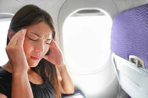 photo of a woman holding her head on an airplane.