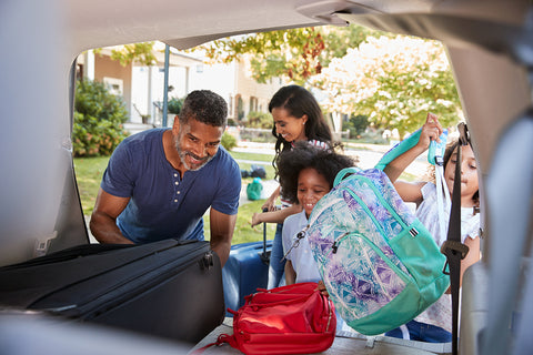 photo of a family packing up their trunk with suitcases.