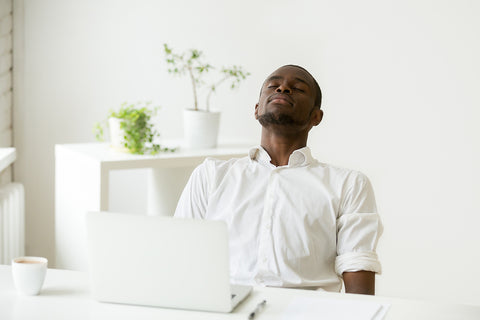 image of a man leaning back at laptop taking a breath.