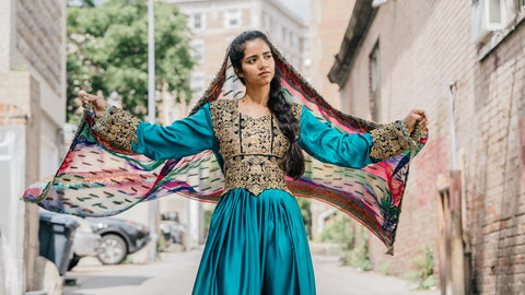 Sonita Alizadeh in colourful dress standing among buildings.