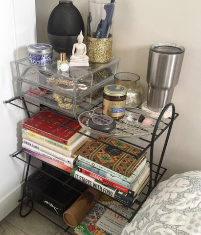 Bedside shelf with books, ornaments, and candles.